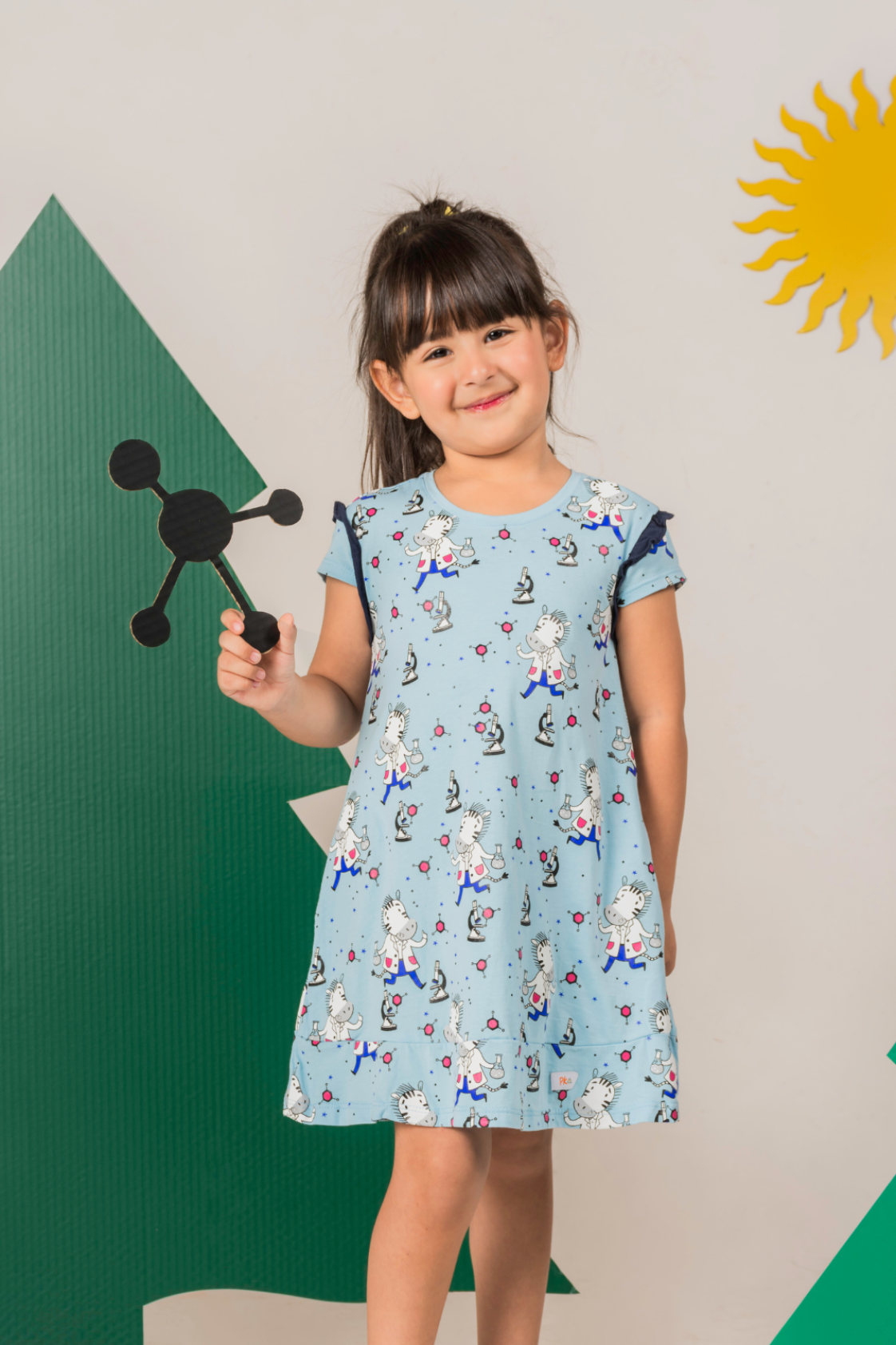 Little girl spinning in a celeste blue and pink A-line dress with a playful scientific zebra motif, short sleeves, and a back button closure.