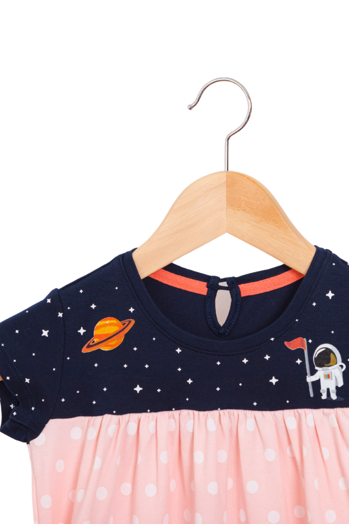 Close up of a soft pink girl's dress with a starry galaxy pattern, detailed Saturn and astronaut prints on the chest, and deep pockets in the skirt.