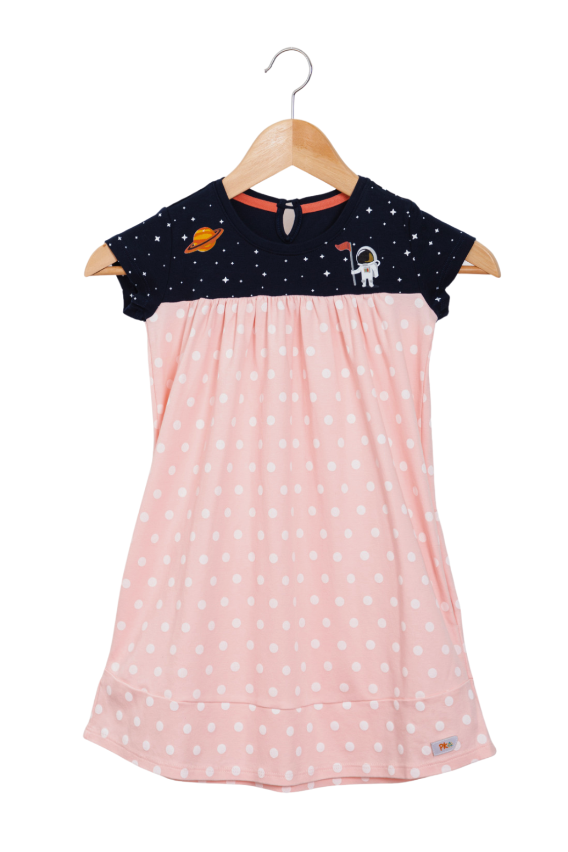 Close up of a soft pink girl's dress with a starry galaxy pattern, detailed Saturn and astronaut prints on the chest, and deep pockets in the skirt.