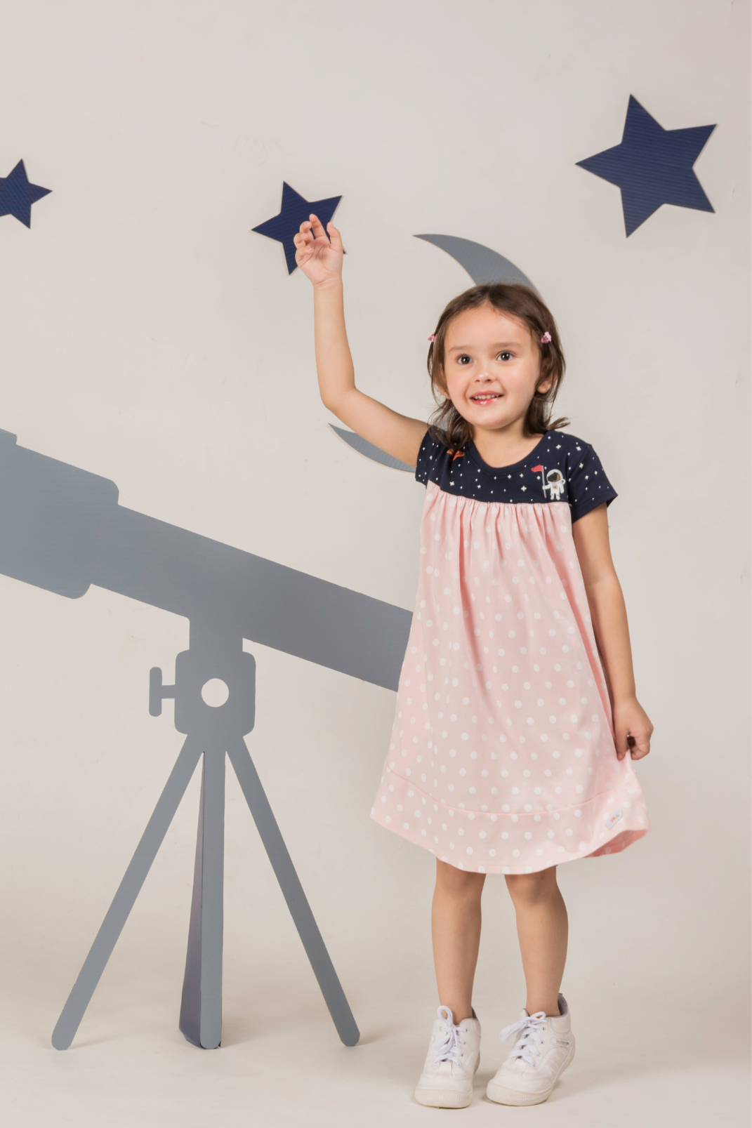 a Litte girl posing with playful expression, and wearing Astro Pink Dress