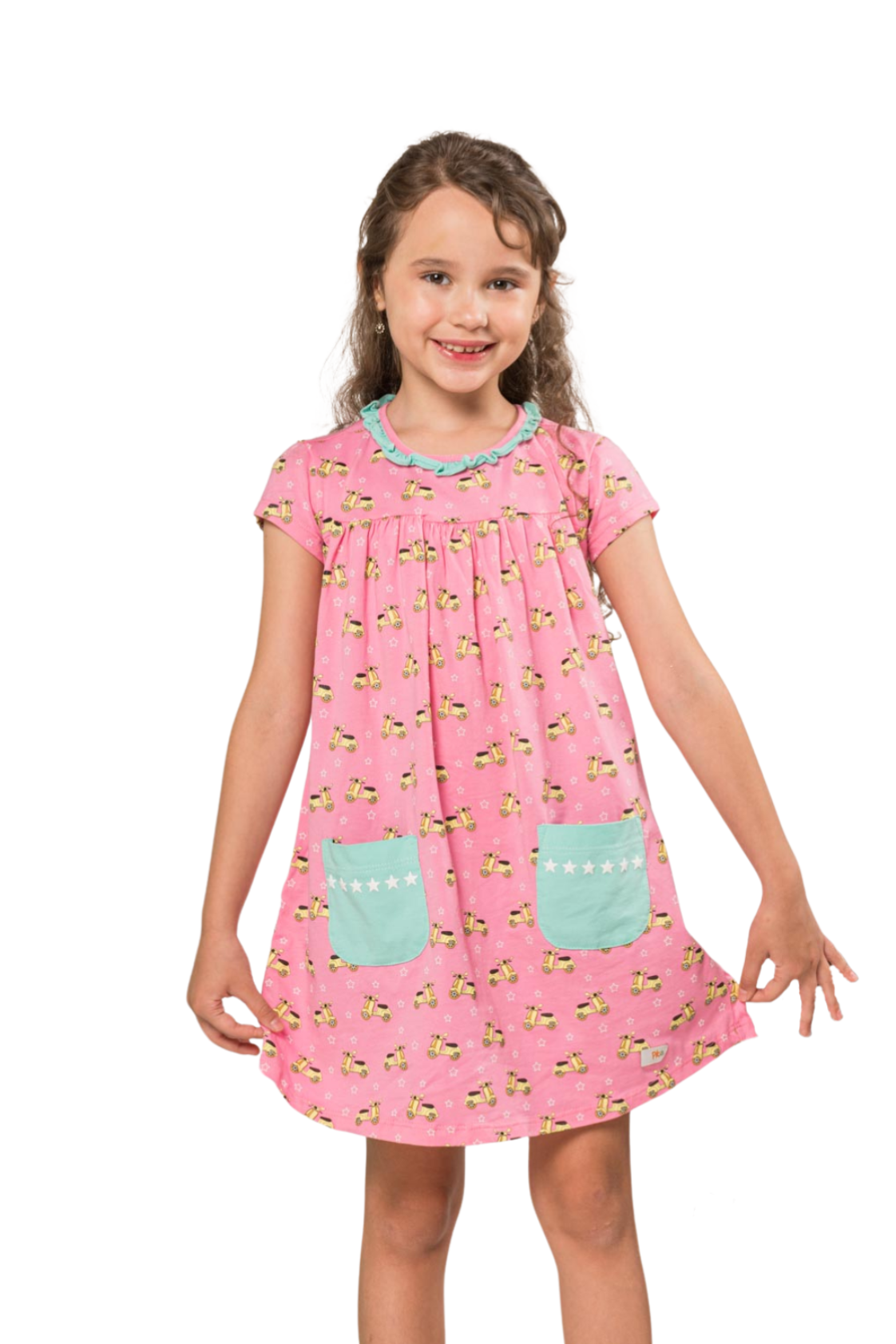 Young girl smiling in a pink empire-silhouette dress covered in scooter and star prints, featuring front pockets and a delicate ruffled neckline.