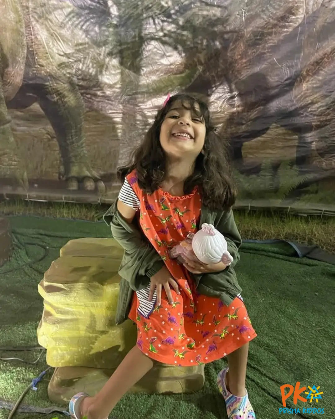 Young girl wearing Dino Coral Dress a vibrant STEM-inspired dress, posing confidently with a smile. 